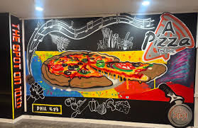 Hand-painted mural inside The Spot on 10th featuring a colorful pizza slice, a red food truck, music notes, and 'The Spot on 10th' lettering